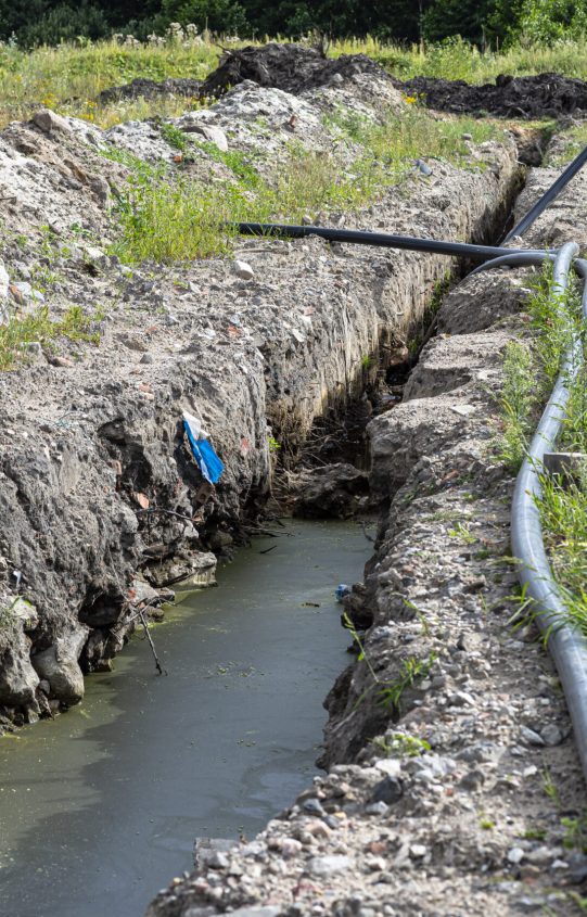 Plastic water pipe lying along the ditch with high groundwater, water connection in the housing estate.