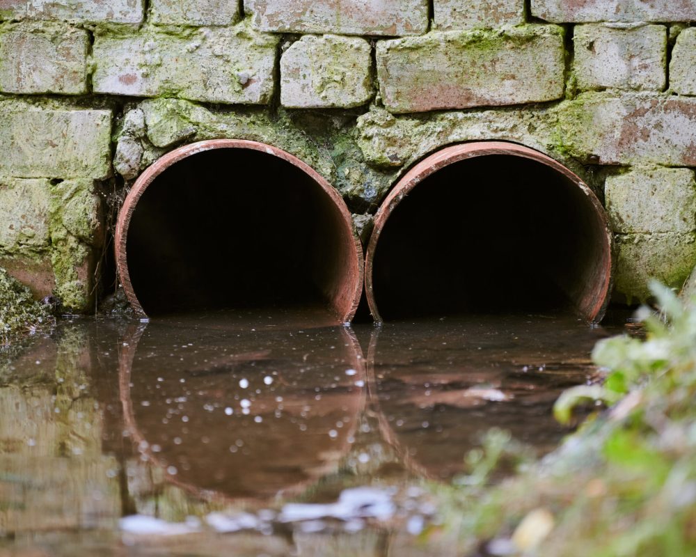 Sewers with toxic dirty water from metal pipes. Draining water from city sewer. Environmental pollution